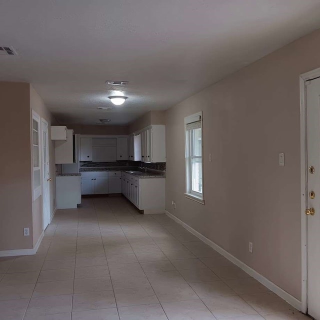 kitchen with white cabinets, light tile patterned floors, and sink