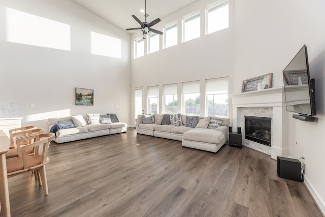 living room featuring ceiling fan, hardwood / wood-style flooring, a high ceiling, and a fireplace