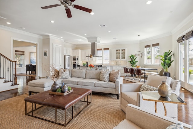 living room featuring light hardwood / wood-style flooring, ceiling fan, and ornamental molding