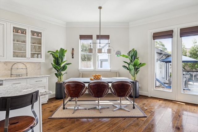 dining space with ornamental molding, an inviting chandelier, and dark wood-type flooring