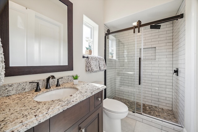 bathroom featuring vanity, tile patterned flooring, toilet, and a shower with door