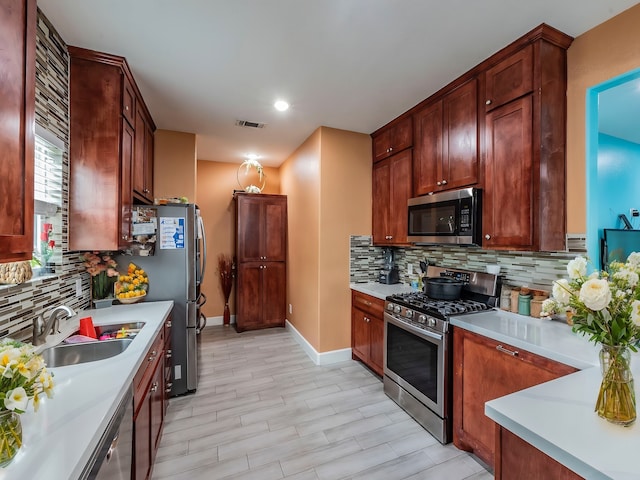 kitchen featuring appliances with stainless steel finishes, sink, light hardwood / wood-style flooring, and tasteful backsplash