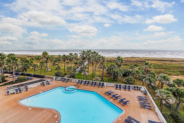 view of swimming pool featuring a view of the beach, a water view, and a patio area