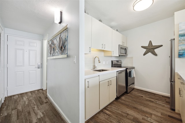 kitchen featuring sink, backsplash, white cabinetry, stainless steel appliances, and dark hardwood / wood-style flooring