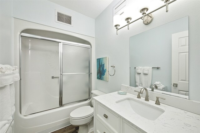 full bathroom with wood-type flooring, combined bath / shower with glass door, vanity, and toilet