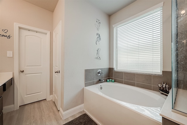 bathroom with wood-type flooring, a bath, and vanity