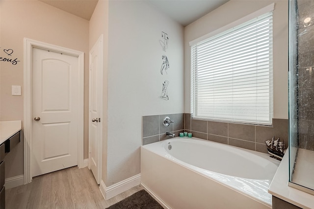 4731 Seabourne Landing Dr, Rosenberg, TX 77469 - bathroom featuring a garden tub, wood finished floors, baseboards, and vanity