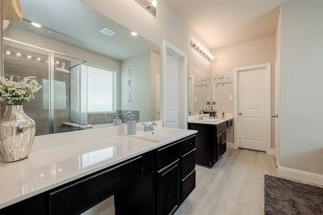 bathroom with wood-type flooring, vanity, and an enclosed shower