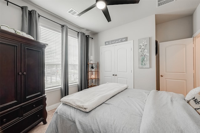 bedroom with ceiling fan, light colored carpet, and a closet