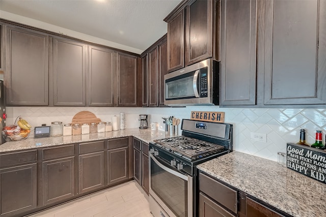 kitchen with dark brown cabinets, appliances with stainless steel finishes, light stone countertops, and tasteful backsplash