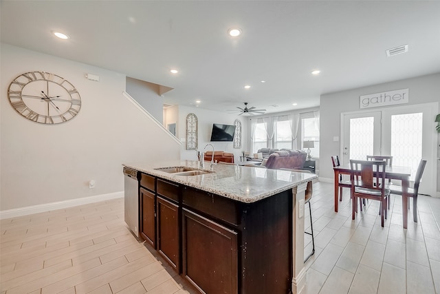 kitchen featuring light wood-type flooring, dishwasher, a kitchen island with sink, sink, and ceiling fan