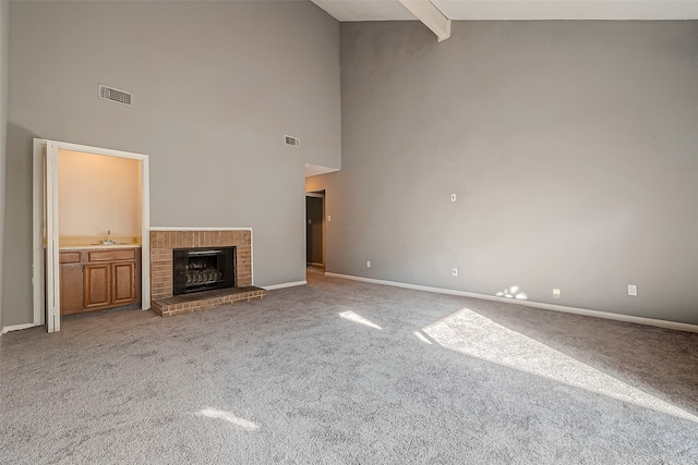 unfurnished living room with a fireplace, light carpet, beamed ceiling, and high vaulted ceiling