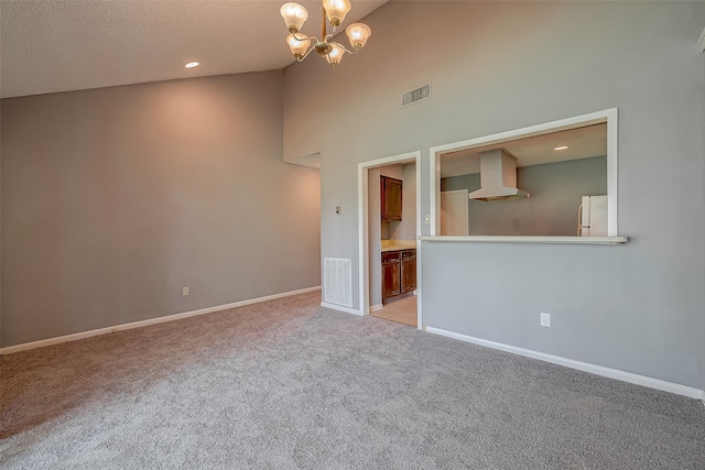 unfurnished living room with a textured ceiling, an inviting chandelier, light carpet, and high vaulted ceiling