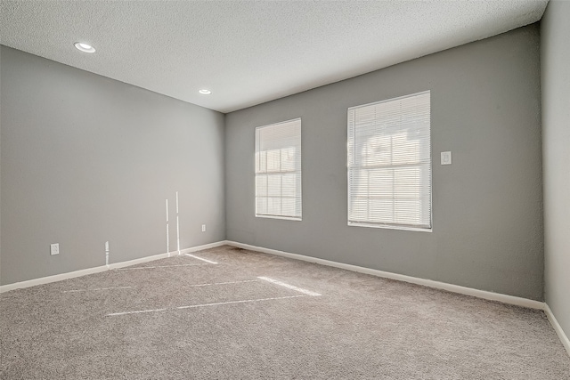 carpeted spare room with a textured ceiling