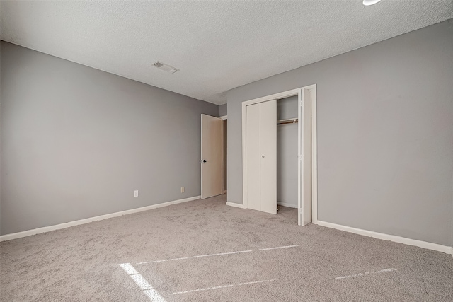 unfurnished bedroom featuring a textured ceiling, light carpet, and a closet