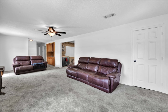 carpeted living room with ceiling fan and a textured ceiling