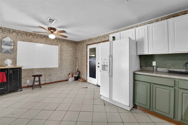 kitchen featuring a textured ceiling, white refrigerator with ice dispenser, white cabinets, light tile patterned floors, and ceiling fan