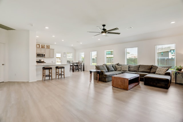 living room featuring ceiling fan, light hardwood / wood-style floors, and plenty of natural light