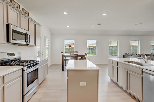 kitchen with a center island, cream cabinets, sink, light hardwood / wood-style flooring, and appliances with stainless steel finishes