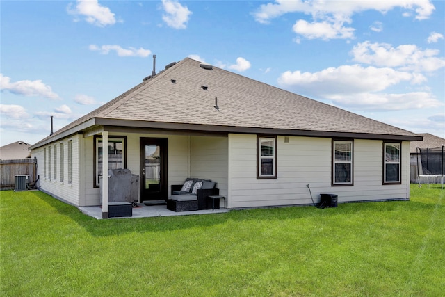 rear view of house with a trampoline, cooling unit, a patio area, and a lawn