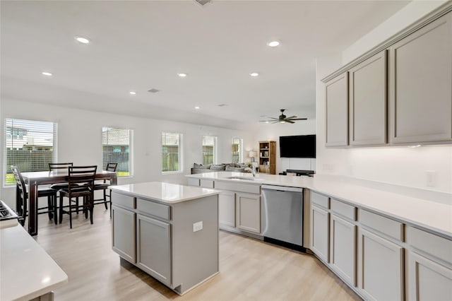 kitchen featuring light wood-type flooring, ceiling fan, sink, dishwasher, and gray cabinets