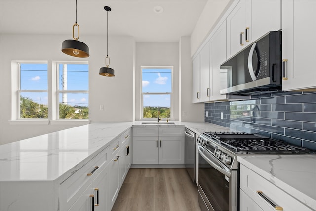 kitchen with appliances with stainless steel finishes, plenty of natural light, sink, and white cabinets