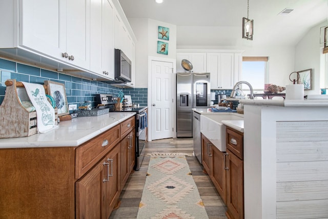 kitchen featuring light hardwood / wood-style flooring, white cabinets, appliances with stainless steel finishes, and hanging light fixtures