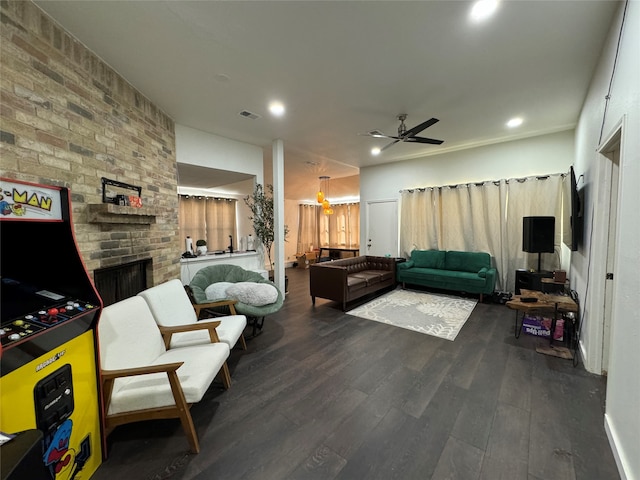 living room with a fireplace, ceiling fan, and dark wood-type flooring