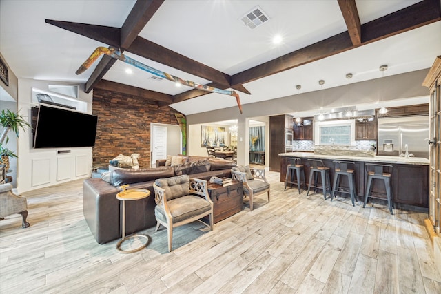 living room with beamed ceiling, light hardwood / wood-style floors, and a healthy amount of sunlight