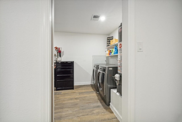 washroom featuring visible vents, washing machine and dryer, wood finished floors, laundry area, and baseboards