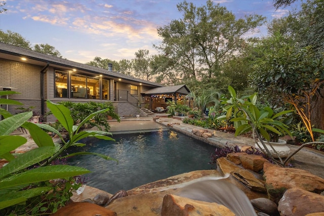 pool at dusk featuring an outdoor pool and a patio