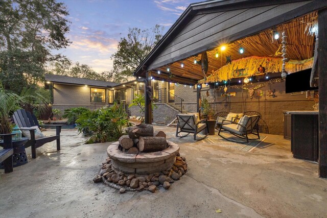 patio terrace at dusk with an outdoor living space with a fire pit