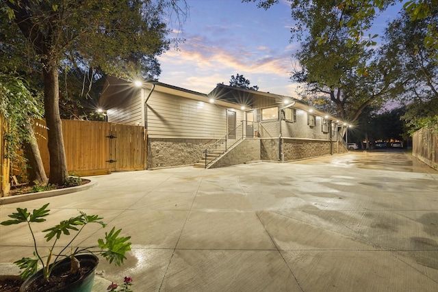 5 Tree Frog Dr, Houston, TX 77074 - back of house at dusk featuring fence, a gate, stairway, and stone siding
