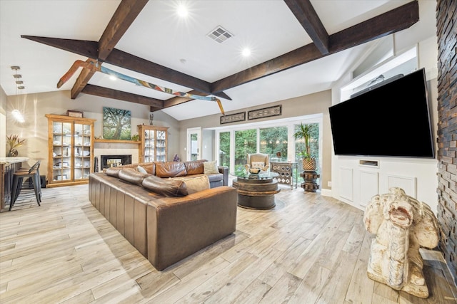 living room with vaulted ceiling with beams and light hardwood / wood-style flooring