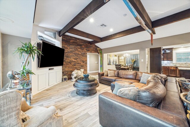 living room with beam ceiling, light wood-type flooring, and a notable chandelier