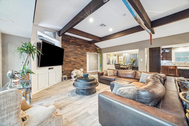 living room with lofted ceiling with beams, light wood finished floors, visible vents, and an inviting chandelier