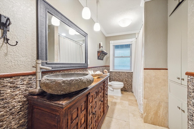 full bathroom with toilet, vanity, tile walls, ornamental molding, and wainscoting