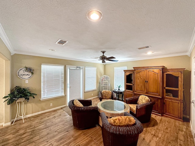 living room featuring light wood-type flooring, ornamental molding, and ceiling fan