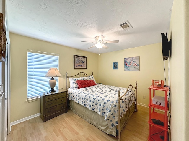 bedroom with ceiling fan, a textured ceiling, and light hardwood / wood-style flooring