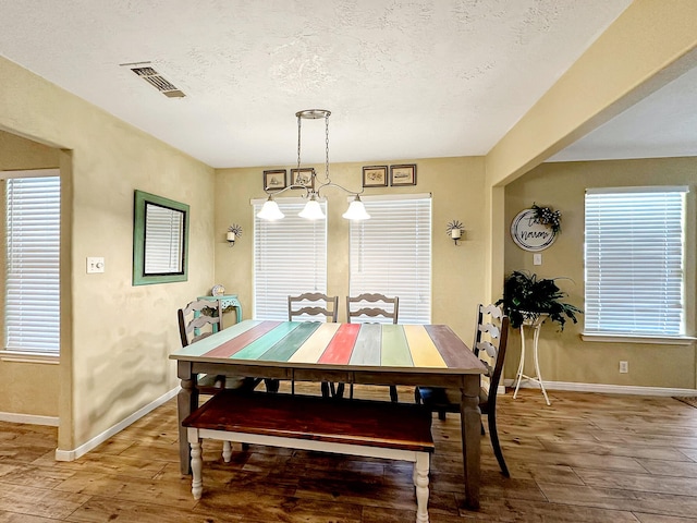 dining space with a notable chandelier, a textured ceiling, and hardwood / wood-style flooring