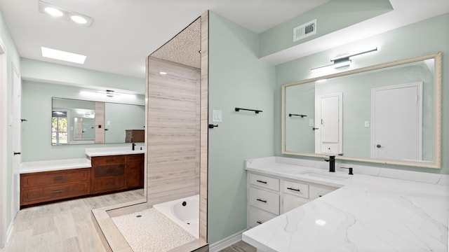 bathroom with wood-type flooring, vanity, a skylight, and a bathtub