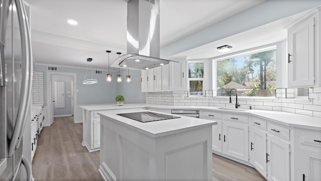 kitchen with sink, a center island, kitchen peninsula, island exhaust hood, and appliances with stainless steel finishes