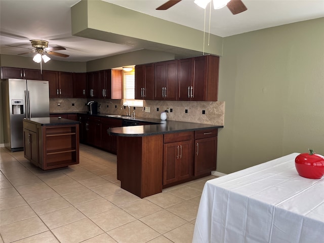 kitchen featuring ceiling fan, sink, a kitchen island, and stainless steel fridge