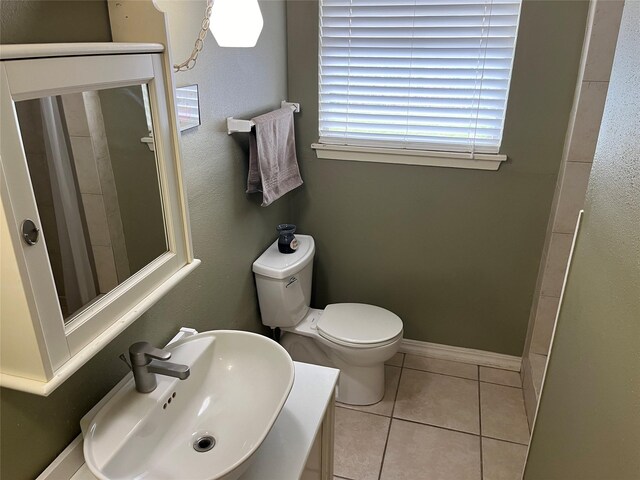 bathroom with toilet, sink, and tile patterned floors