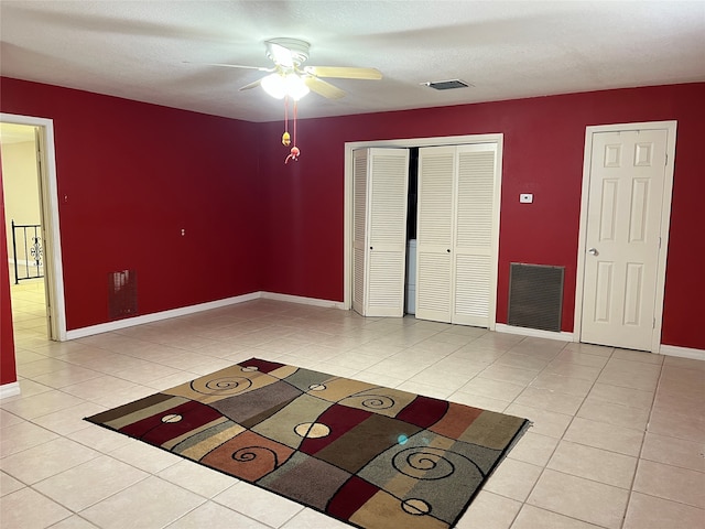 tiled spare room with ceiling fan and a textured ceiling