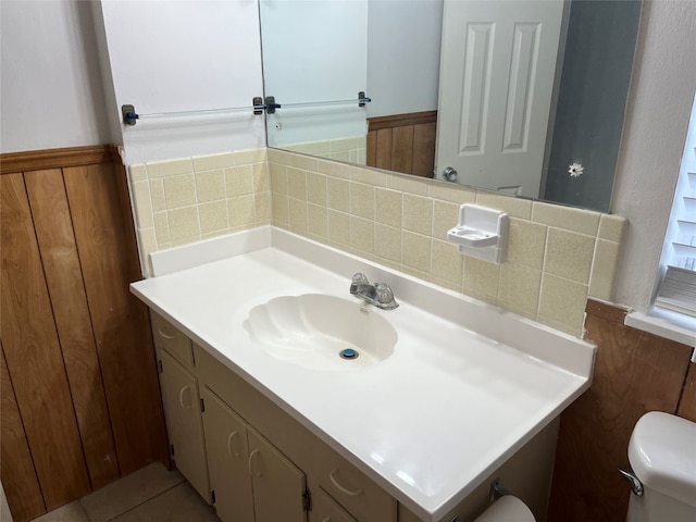 bathroom with vanity, wooden walls, toilet, and tasteful backsplash