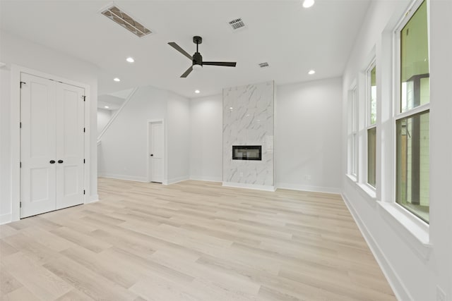 unfurnished living room with a premium fireplace, light hardwood / wood-style floors, and ceiling fan