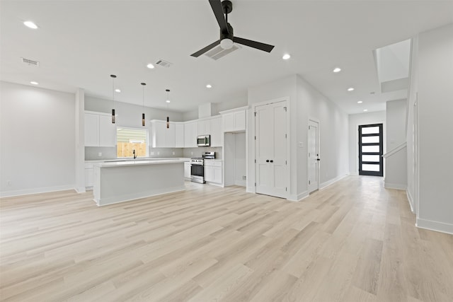 unfurnished living room with light wood-type flooring, ceiling fan, and sink