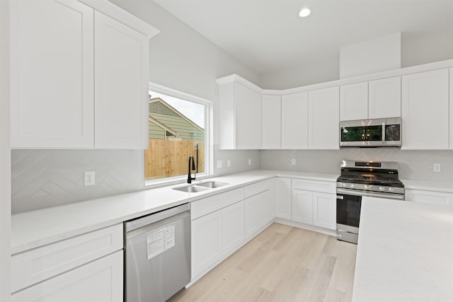 kitchen featuring stainless steel appliances, white cabinets, light wood-type flooring, and sink