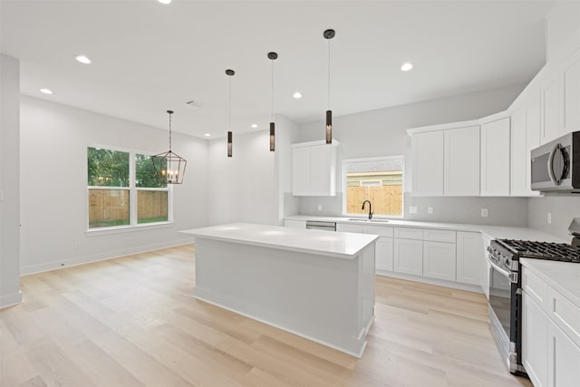 kitchen with pendant lighting, appliances with stainless steel finishes, white cabinetry, and a kitchen island